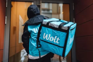 عامل توصيل يحمل صندوق عليه علامة تطبيق والت Wolt
